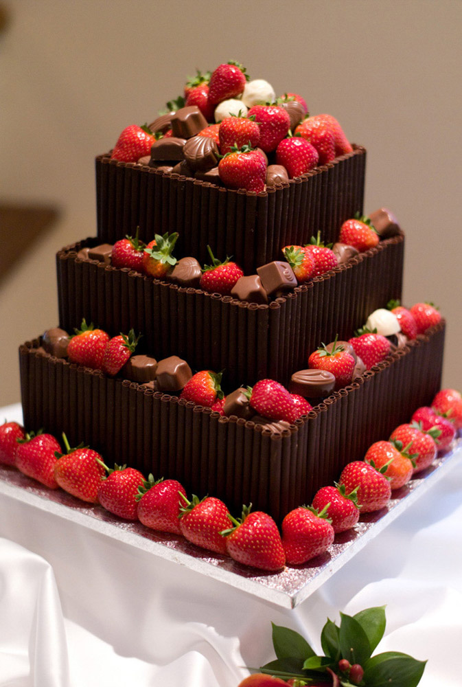 Wedding cake decorated with strawberries and chocolates at an evening reception—beautiful natural wedding detail captured in true colour.